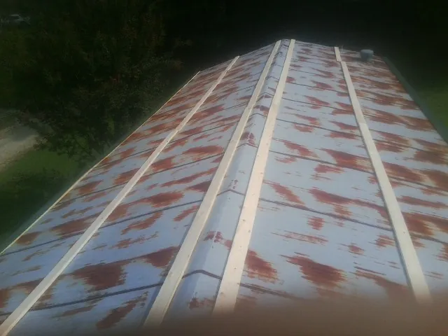 Rusted metal roof panels with new wood purlins before replacement in Truro