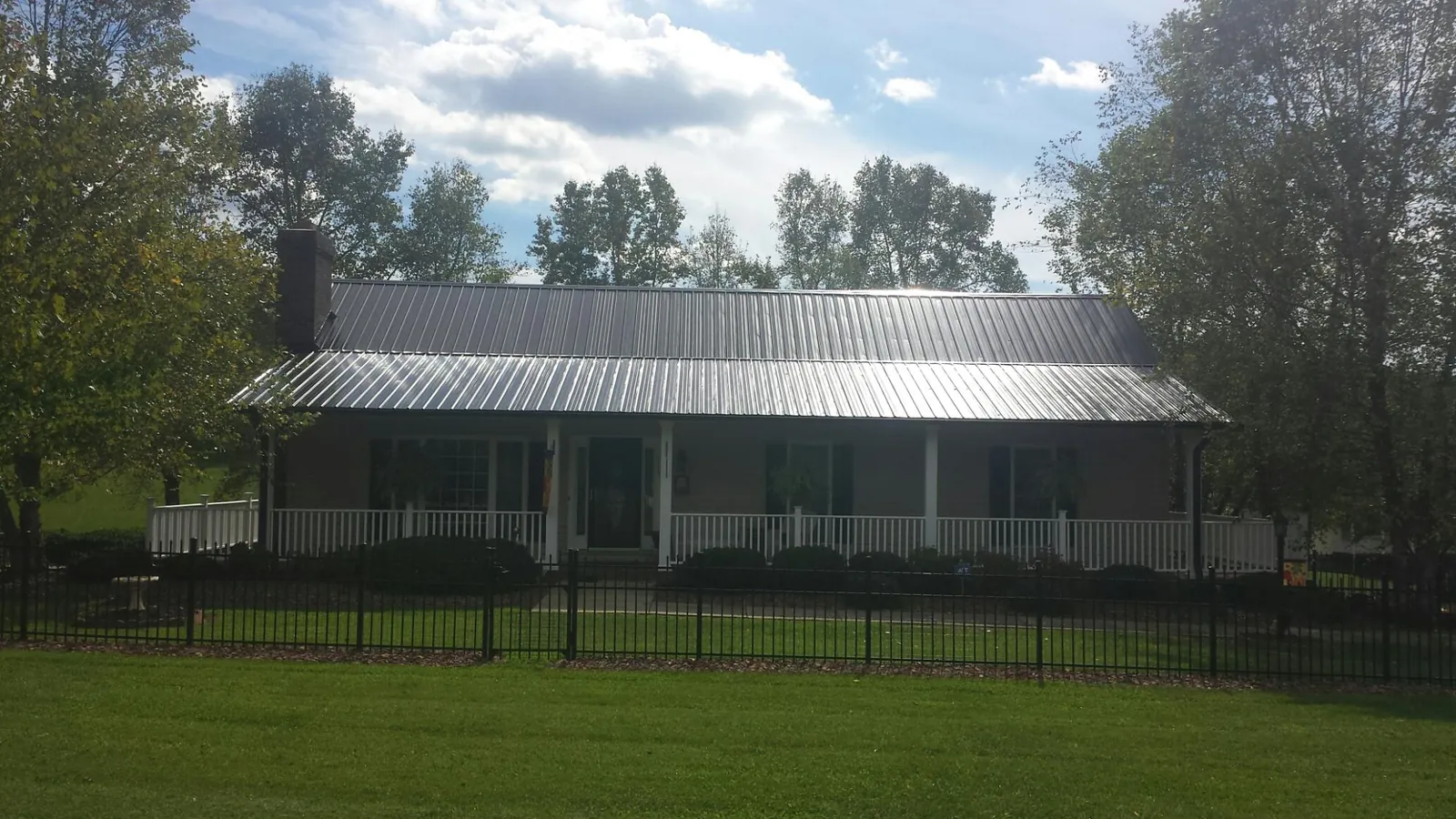 Gray metal roof on a brick ranch with a full width front porch — Gutter Guard Installation work by our crew in Truro