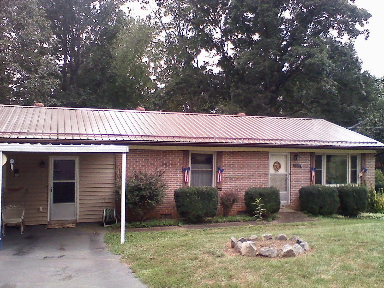 Bronze metal roof and carport on a brick ranch home — Roof Repair work by our crew in Truro