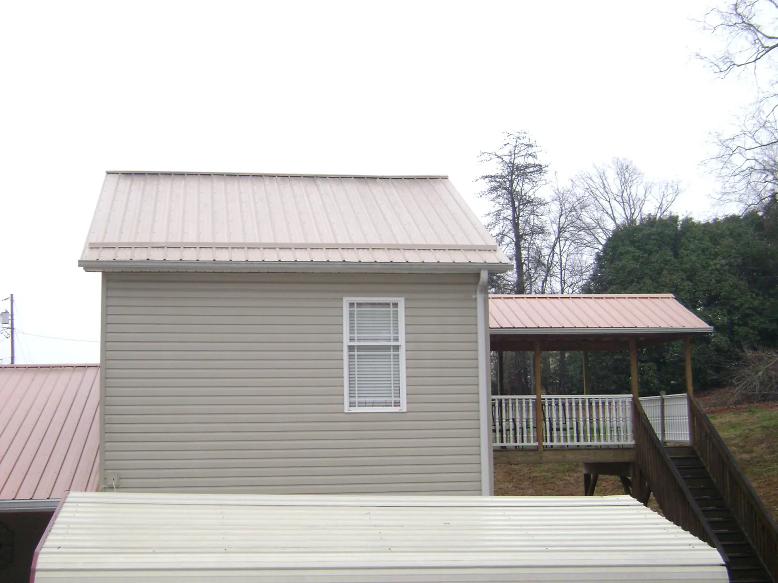 Tan metal roofs on a two story addition and attached porch, from a Roof Replacement job in Truro